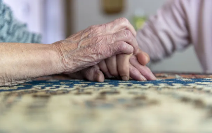Elderly woman holding her daughter hand in a caring embrace
